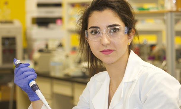 Parinaz Emami in lab coat coducting research.