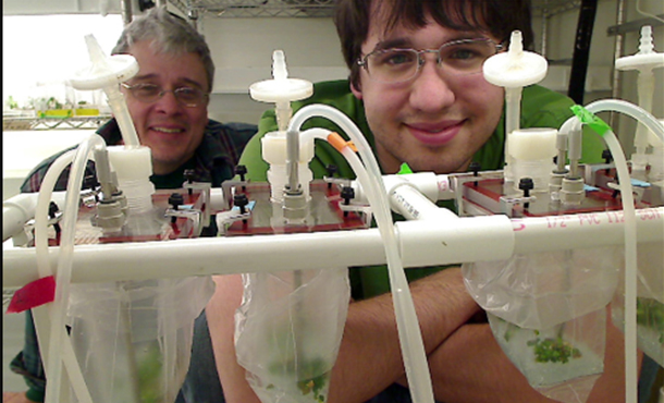 wayne curtis, glasses, white curly hair with student with brown hair, glasses, in a lab with lab equipment, bottles