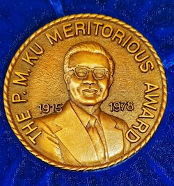 P.M. Ku medal on a blue background