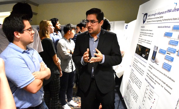 poster presenter explaining his poster to two attendees