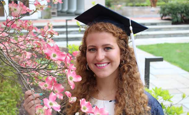 Bailyn Bench in graduation cap posing with flowering tree
